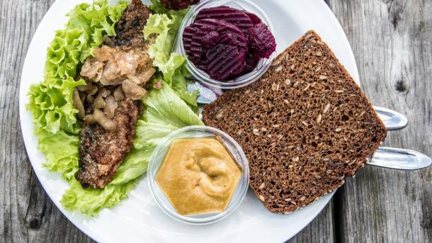 Tallerken med klassisk dansk smørrebrød med sild og frikadelle på et bord