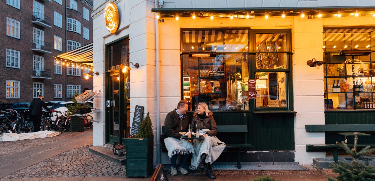 Et par sitter på en benk utenfor en kafe i København på vinteren