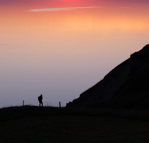 A hiker enjoying the view and sunset over Limfjorden from Hanklit on Mors.