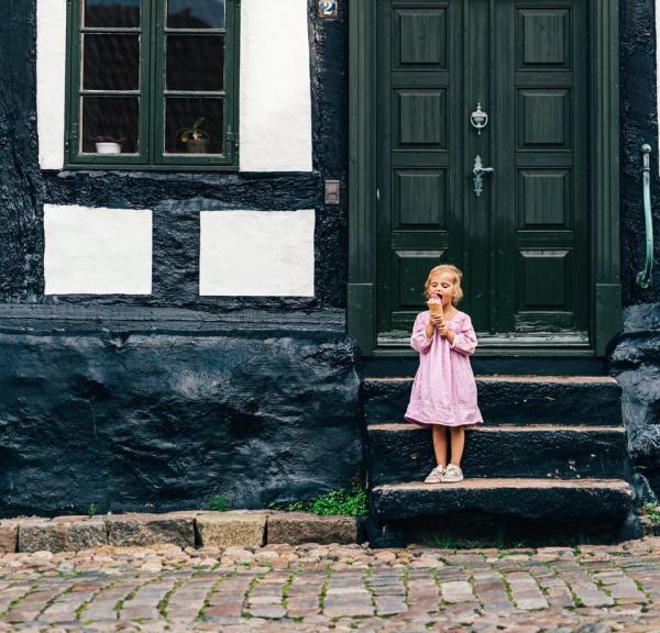 A little child eats ice cream on the stairs in front of a house, Ebeltoft