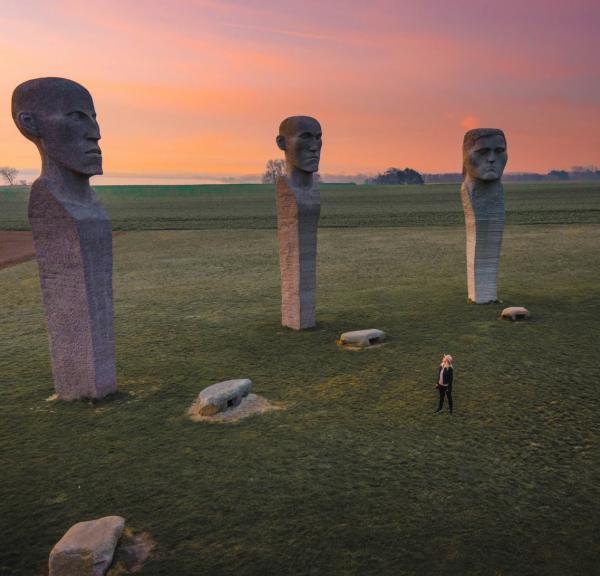 Person looking at stone sculptures Dodekalitten during sunset on Lolland-Falster, Denmark